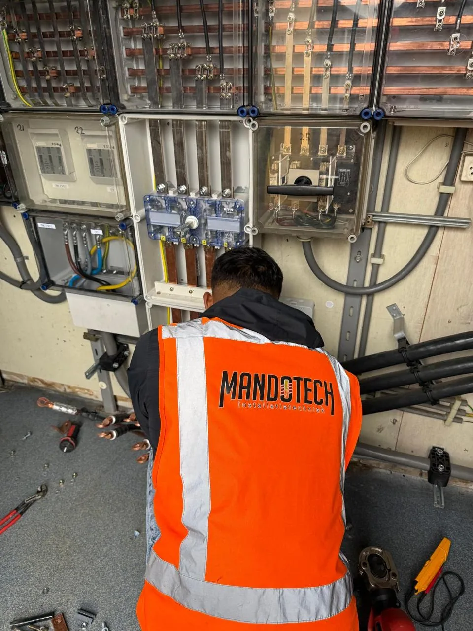 Mandotech monteur in bedrijfskleding werkt aan een verdeelinrichting